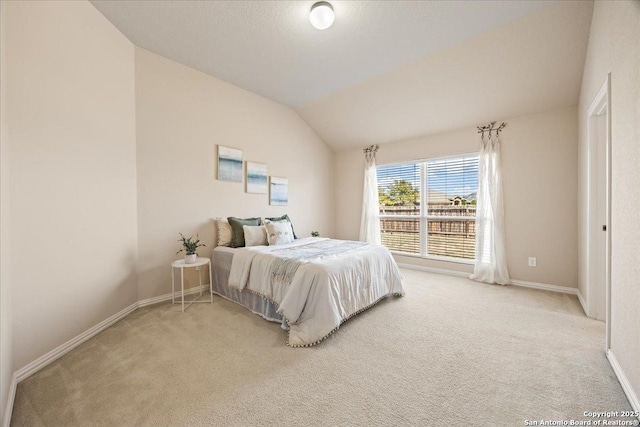 bedroom featuring lofted ceiling, light colored carpet, and baseboards