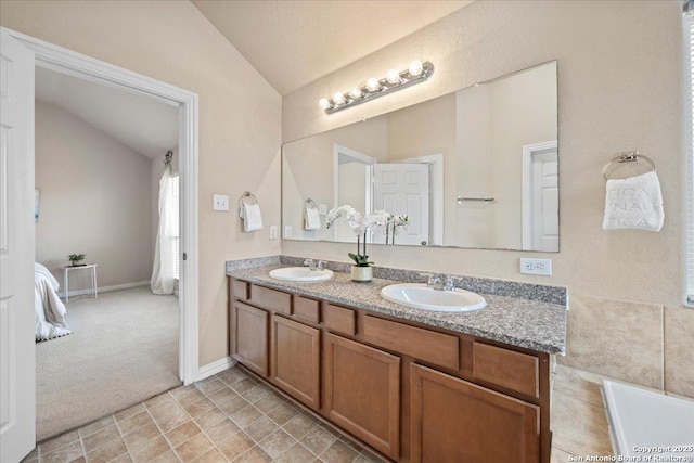 bathroom featuring double vanity, a sink, baseboards, and vaulted ceiling