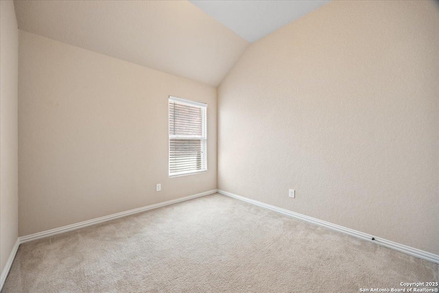 empty room with carpet flooring, baseboards, and lofted ceiling