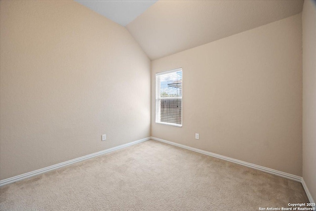 carpeted empty room with baseboards and lofted ceiling