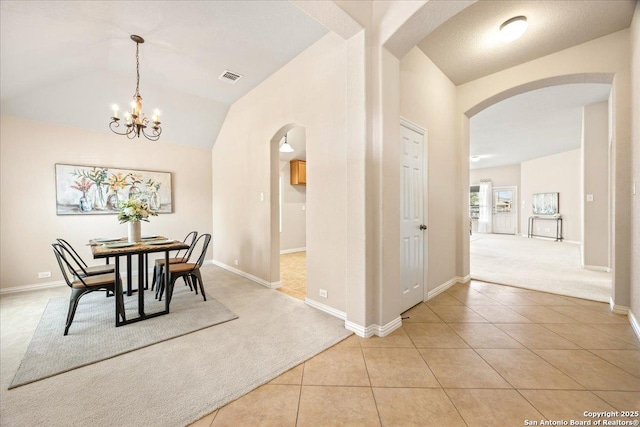 dining area featuring light tile patterned floors, visible vents, arched walkways, and light colored carpet