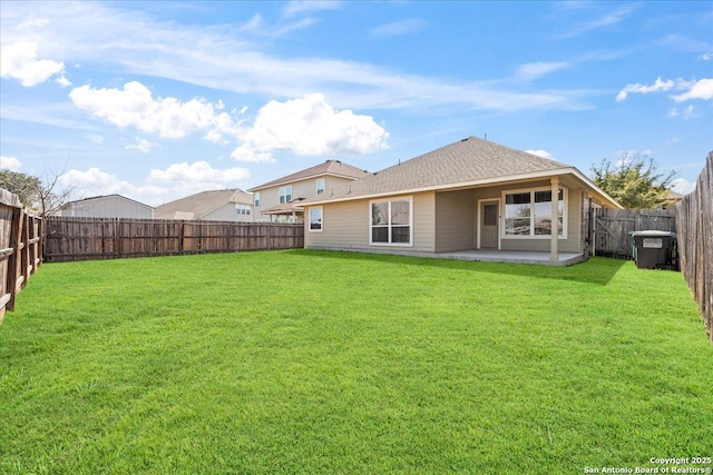 back of property featuring a lawn, a patio, a shingled roof, and a fenced backyard