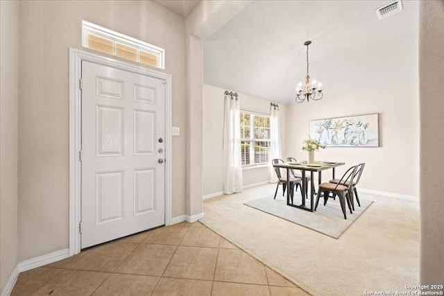 entrance foyer with carpet, visible vents, baseboards, tile patterned flooring, and a notable chandelier