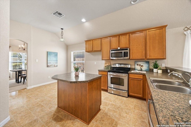 kitchen with visible vents, a sink, appliances with stainless steel finishes, dark countertops, and brown cabinets