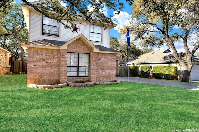 traditional home featuring a front lawn, fence, brick siding, and aphalt driveway