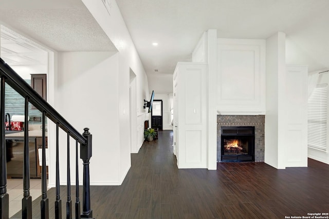 unfurnished living room featuring baseboards, stairs, recessed lighting, a warm lit fireplace, and wood finished floors