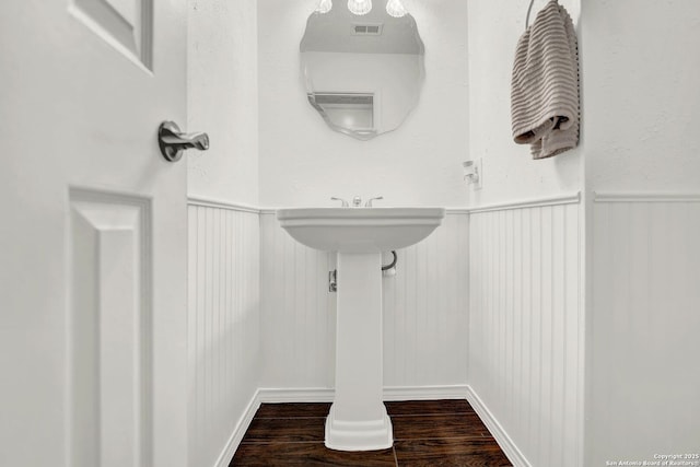 bathroom featuring visible vents, wood finished floors, and a wainscoted wall