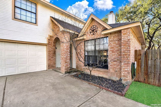 view of front of house with a garage, brick siding, a chimney, and fence