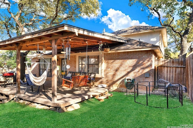 back of property with a deck, a yard, fence, and brick siding