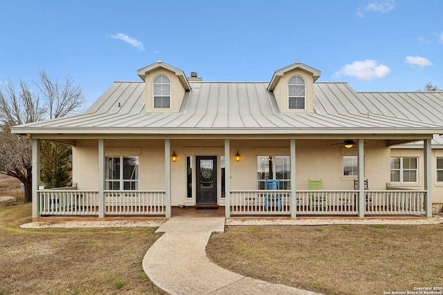 view of front facade with stucco siding, a porch, metal roof, and a standing seam roof