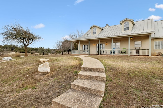 view of front of home with a standing seam roof, a porch, stucco siding, a front lawn, and metal roof