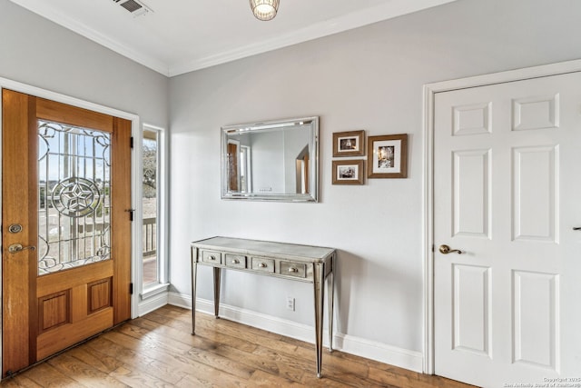 entrance foyer featuring visible vents, hardwood / wood-style flooring, baseboards, and ornamental molding