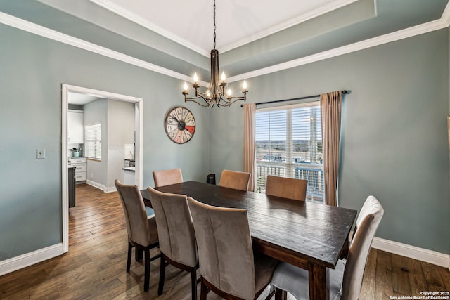 dining room featuring a tray ceiling, baseboards, dark wood-style floors, and ornamental molding