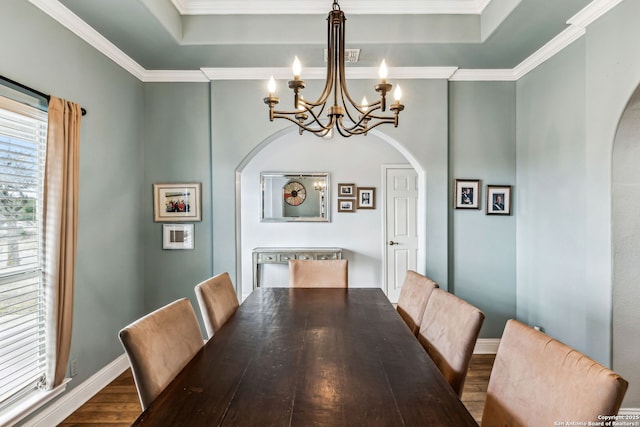 dining area featuring arched walkways, an inviting chandelier, a tray ceiling, and wood finished floors