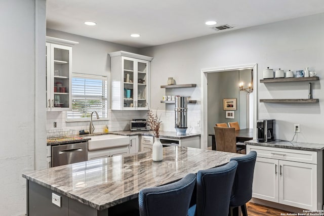 kitchen featuring backsplash, open shelves, dishwasher, white cabinets, and a sink