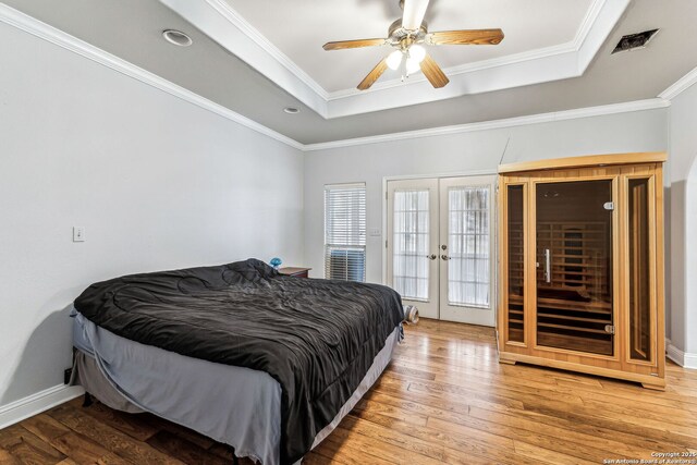 bedroom featuring a tray ceiling, hardwood / wood-style floors, and french doors