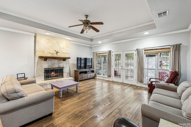 living area featuring a tray ceiling, visible vents, hardwood / wood-style floors, and french doors