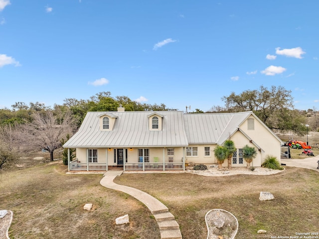 view of front of property with a porch, stucco siding, a chimney, metal roof, and a standing seam roof