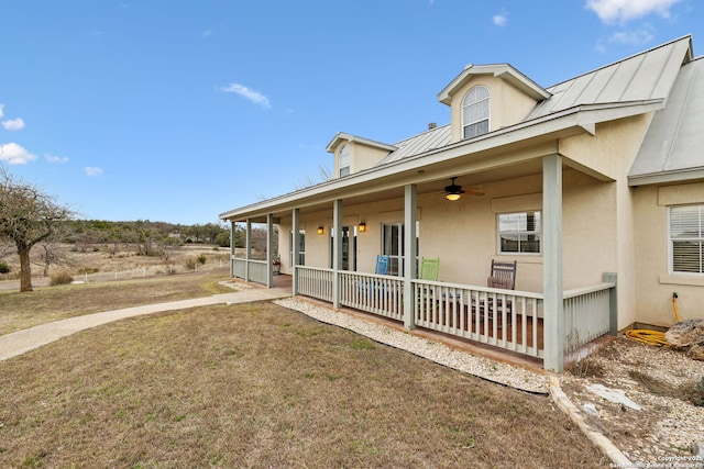 view of front of home featuring stucco siding, a front lawn, a ceiling fan, a standing seam roof, and metal roof