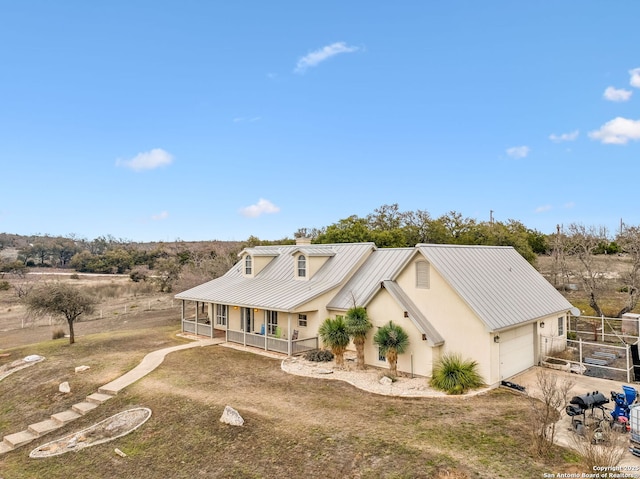 view of front facade featuring stucco siding, a standing seam roof, a porch, metal roof, and a garage