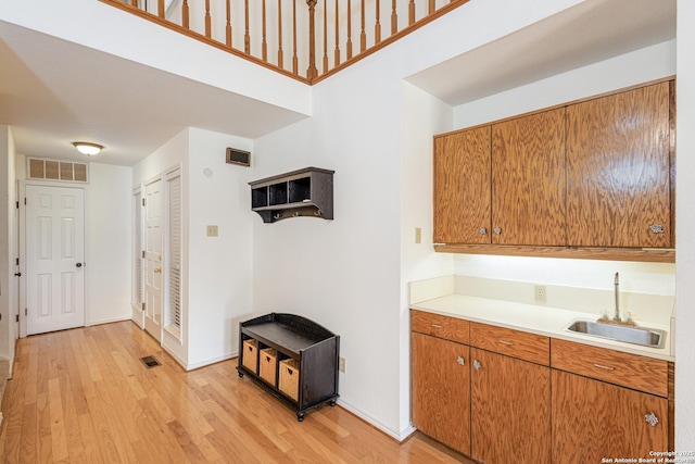 kitchen featuring brown cabinetry, visible vents, a sink, light countertops, and light wood finished floors