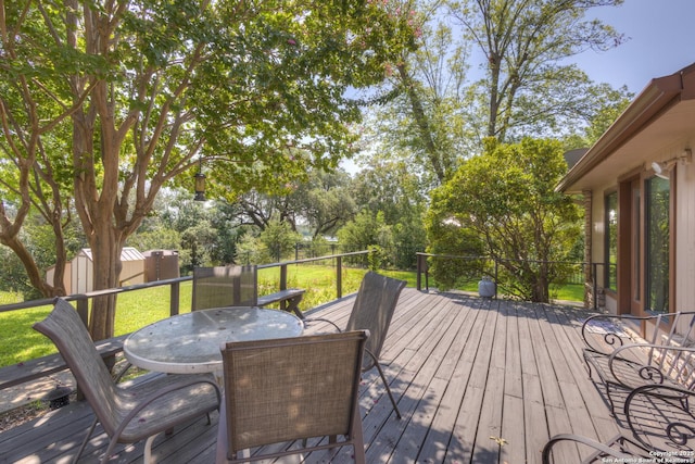 deck featuring outdoor dining area, an outdoor structure, a lawn, and a shed