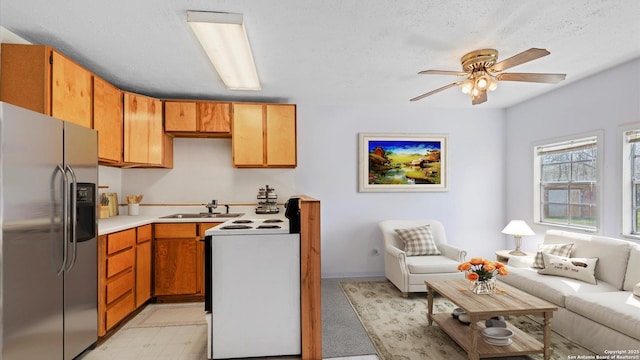 kitchen with a ceiling fan, white range with electric cooktop, open floor plan, stainless steel fridge with ice dispenser, and light countertops