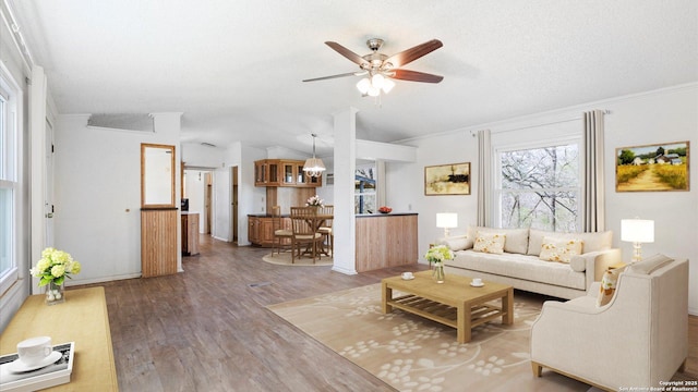 living area featuring a ceiling fan, wood finished floors, vaulted ceiling, a textured ceiling, and crown molding