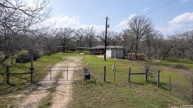 exterior space featuring an outdoor structure, a gate, fence, and dirt driveway