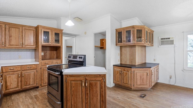 kitchen featuring light wood-style flooring, stainless steel range with electric stovetop, an AC wall unit, and brown cabinets