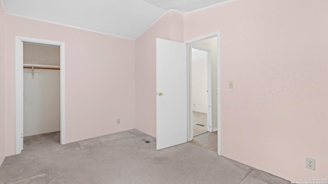 unfurnished bedroom with a closet, crown molding, carpet, and vaulted ceiling