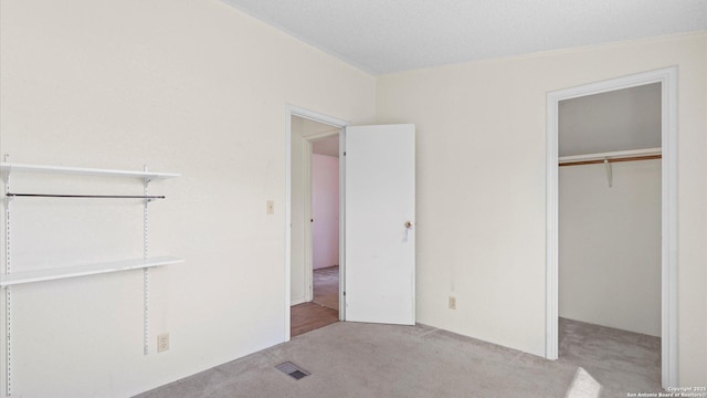 unfurnished bedroom with visible vents, carpet floors, a closet, and a spacious closet