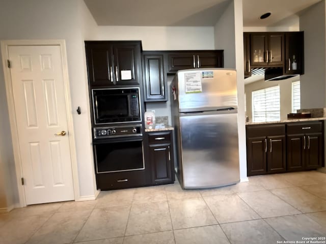 kitchen with dark brown cabinetry, light tile patterned floors, black appliances, and light stone countertops