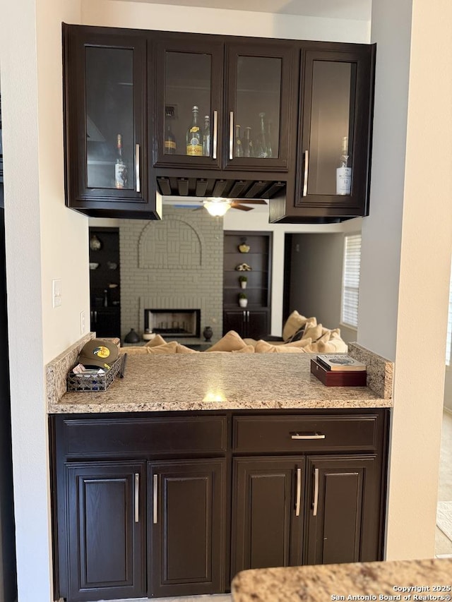 kitchen featuring a peninsula, decorative backsplash, dark brown cabinetry, glass insert cabinets, and open floor plan