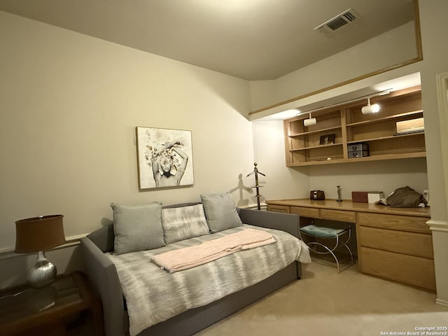 interior space featuring visible vents, light colored carpet, and built in desk