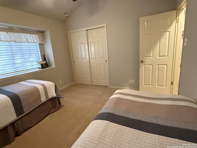 bedroom featuring a closet, light colored carpet, baseboards, and lofted ceiling