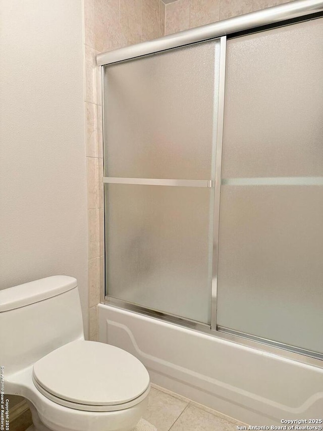 bathroom featuring enclosed tub / shower combo, toilet, and tile patterned flooring