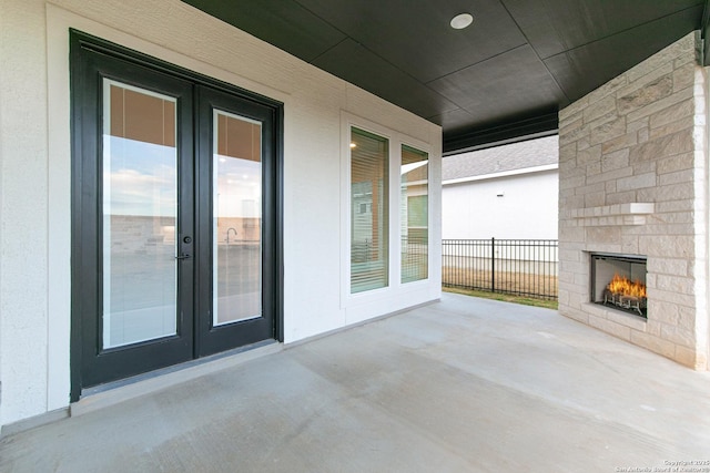 view of patio / terrace with french doors, fence, and an outdoor stone fireplace