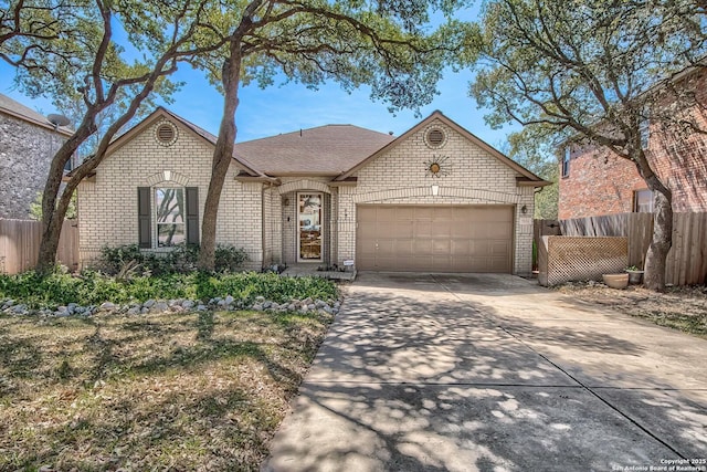 french country style house with brick siding, an attached garage, concrete driveway, and fence