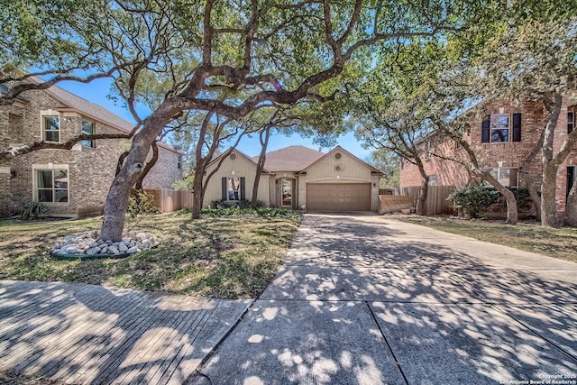 view of front of home with brick siding, an attached garage, driveway, and fence