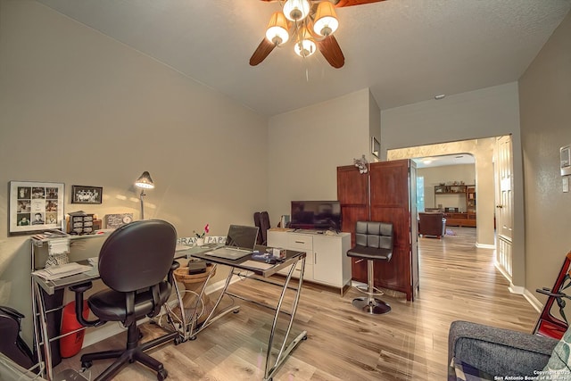 office space featuring ceiling fan, baseboards, arched walkways, and light wood-style flooring