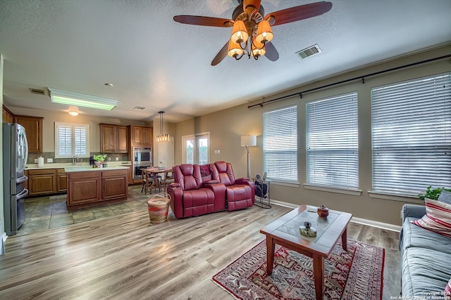 living room featuring visible vents, plenty of natural light, and light wood-style flooring