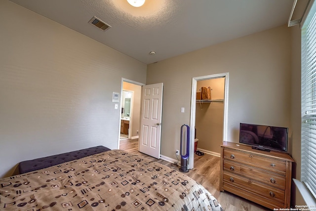 bedroom with visible vents, a walk in closet, baseboards, light wood-style floors, and a closet