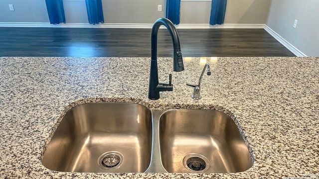 details with a sink, stone counters, baseboards, and dark wood-type flooring