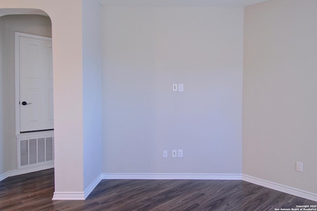 spare room with visible vents, baseboards, arched walkways, and dark wood-style floors