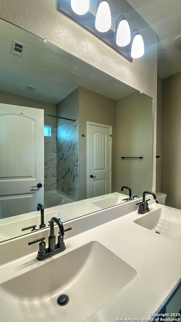 bathroom featuring double vanity, visible vents, and a sink