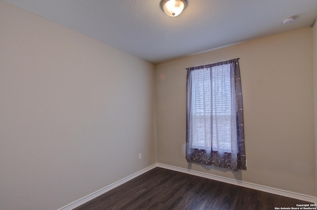 unfurnished room with dark wood-type flooring and baseboards