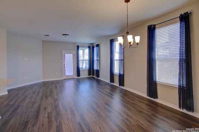 empty room with a chandelier, visible vents, baseboards, and dark wood-style flooring