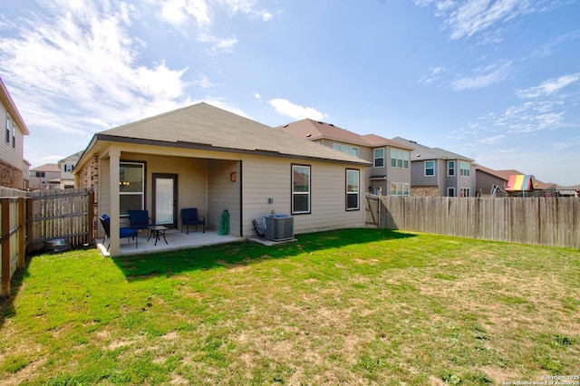 back of house featuring central air condition unit, a patio, a lawn, and a fenced backyard