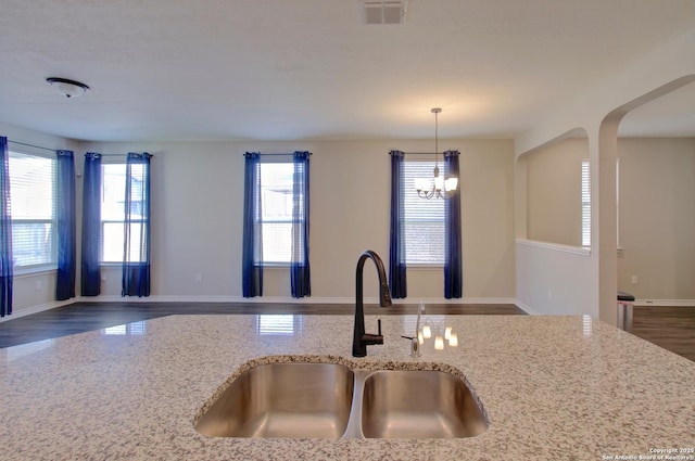 kitchen featuring visible vents, light stone countertops, open floor plan, an inviting chandelier, and a sink